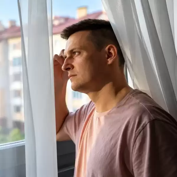 Man standing by a window in a quiet, reflective moment