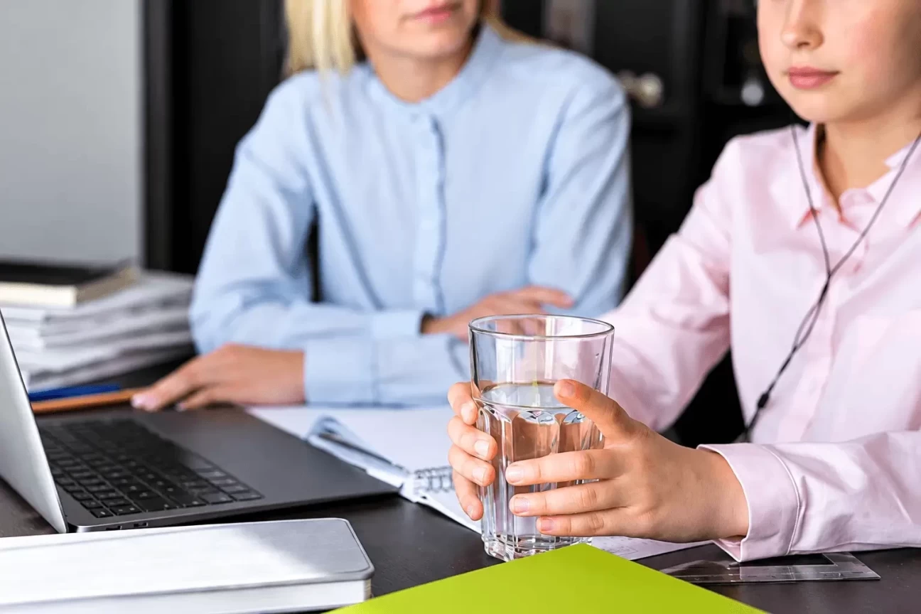 Employee holding a glass of water during a workplace discussion with a colleague