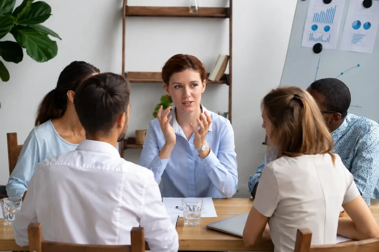 Employee speaking with colleagues during a workplace team meeting about mental health and wellbeing