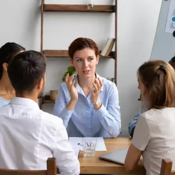 Employee speaking with colleagues during a workplace team meeting about mental health and wellbeing