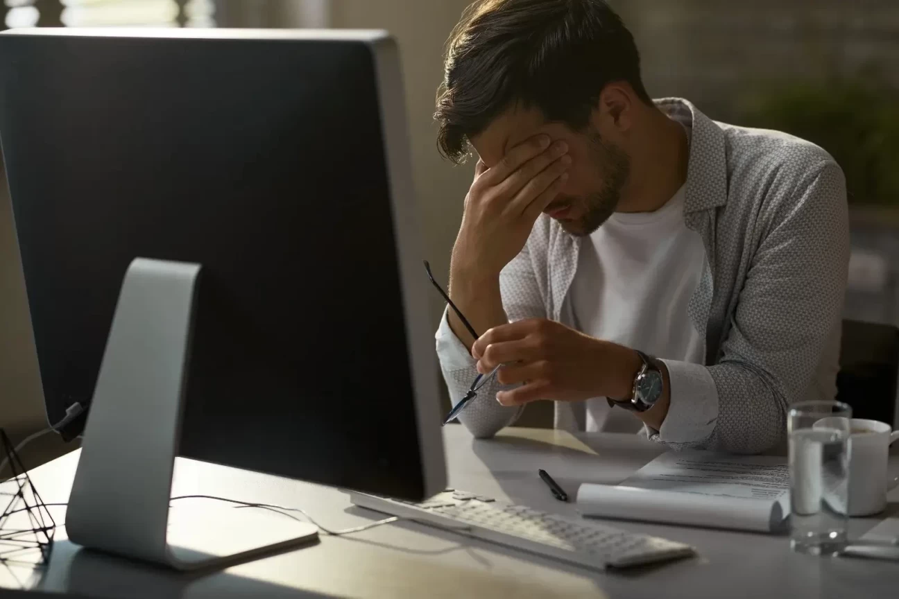 Stressed employee sitting at a desk in front of a computer