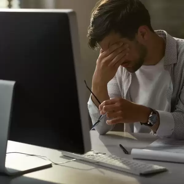 Stressed employee sitting at a desk in front of a computer